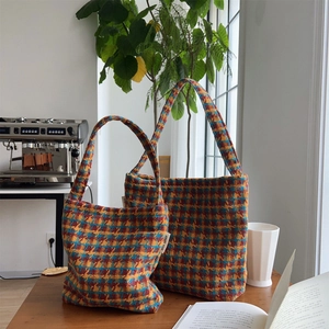 Detailed knit texture and vintage plaid pattern on woven shoulder bags on wood table
