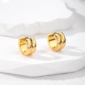 Macro view of gold stainless steel huggie hoop earrings with parallel grooved texture