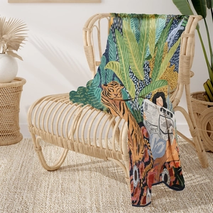 Detail of tropical jungle print throw blanket with tiger and foliage draped on a chair