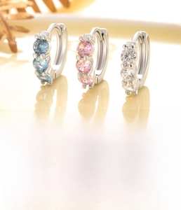 Macro detail of three-piece copper zircon huggie hoop earrings with silver finish