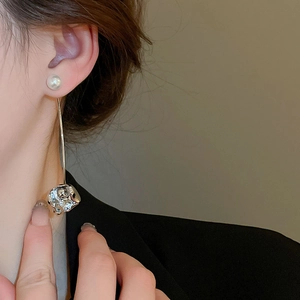 Close-up of elegant long pearl earrings with silver textured geometric pendants on model