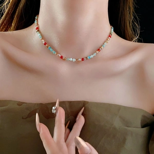 Close-up of a colorful beaded necklace with red blue and gold beads on a model
