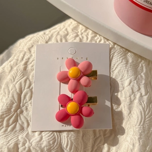 Close-up of pink flower hair clips with yellow centers on a white display card