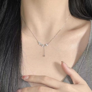Close-up of sparkling zircon leaf pendant necklace with tassel on a model's neck