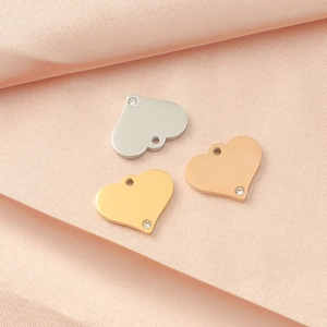 Macro view of heart charms in silver, gold, and rose gold with small crystals on silk