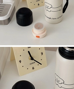 Detail of white insulated mug with cartoon dog print and orange flip-top tea filter lid
