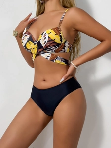 Detail of tropical leaf print bikini top and high-waisted black swim bottoms on model