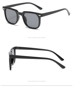 Detail of square black sunglasses with silver arrow rivets and dark gray lenses