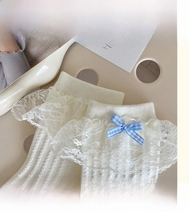 Detailed view of white ballet-style socks with lace trim and blue gingham bow accent