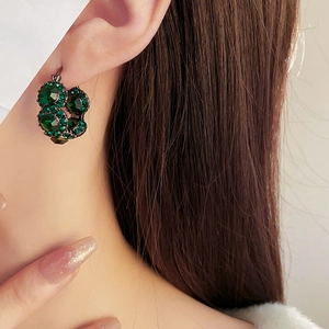 Close-up of French vintage emerald green crystal hoop earrings worn on female ear
