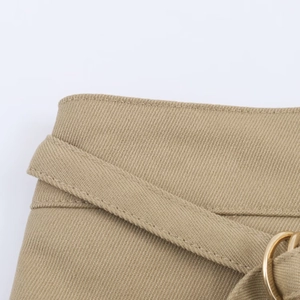 Gros plan sur la jupe-short en sergé kaki avec ceinture et boucle métallique ronde dorée