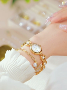 Detailed close-up of gold quartz watch with heart pendant and pearl bracelet