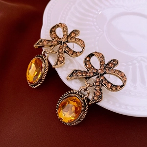 Detail of vintage bow earrings with rhinestones and amber gemstone on a ceramic plate