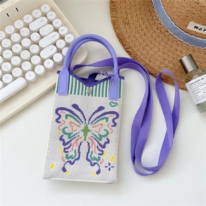 Close-up of cream knitted phone bag with purple handles and colorful butterfly pattern