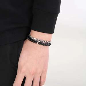 Detail of silver Cuban link chain and black onyx beaded bracelets worn on a wrist