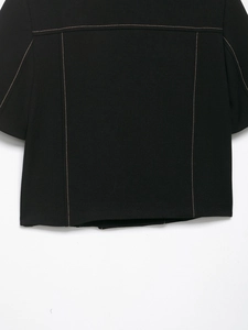 Detailed macro view of black twill blazer featuring golden brown contrast stitching accents