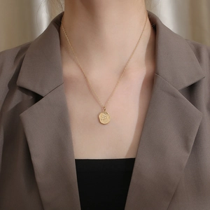 Close-up of a vintage rose flower pendant necklace in gold on a model neck