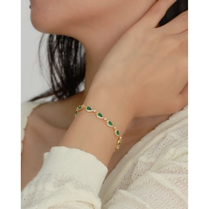 Luxurious gold bracelet with emerald green teardrop stones and sparkling crystals