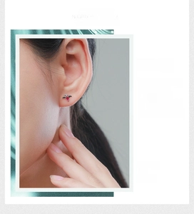 Gros plan d'une boucle d'oreille dinosaure en argent S925 avec gemme rouge