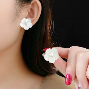 Détail de boucles d'oreilles fleur avec pétales en nacre et une perle centrale