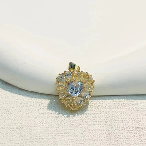 Elegant gold plated heart pendant with micro-inset zircons on white textured background