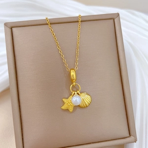 Detailed shot of gold starfish shell and pearl pendant in a cream jewelry box