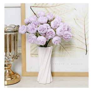 Detailed view of purple silk peonies in a white spiral ceramic vase for home decor