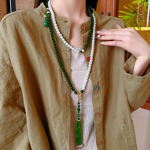 Détail du collier nuage multicouche avec perles blanches et long gland en soie verte