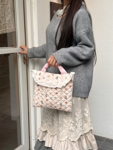 Close-up of pink quilted laptop bag with cute bear patterns and delicate white lace trim