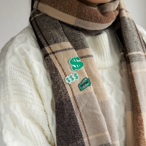Close-up of green financial freedom money-themed pins on a white scarf detail