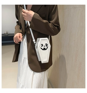 Close-up of a white coffin-shaped crossbody bag with a black pumpkin face print and PU leather