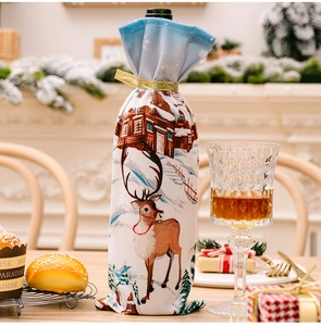Detail of Christmas wine bottle cover with reindeer and winter house print and gold ribbon