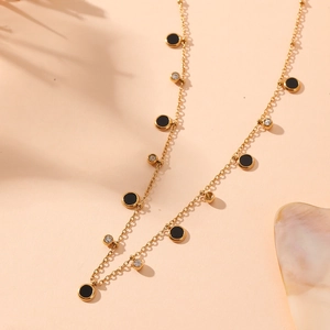Détail du collier doré avec disques en émail noir et strass transparents scintillants