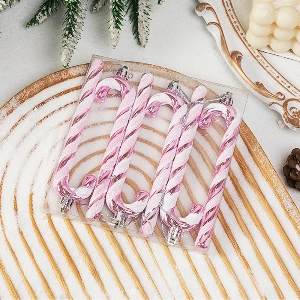 Close-up of pink and white candy cane Christmas tree ornaments with silver hanging ropes