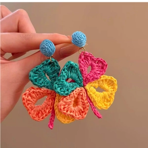 Close-up of colorful raffia woven heart-shaped earrings with bohemian vacation style details