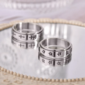 Titanium spinner rings with engraved cross and turtle patterns on mirror tray