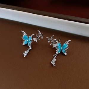 Detail of butterfly earrings with blue glitter wings and clear teardrop zircon pendant