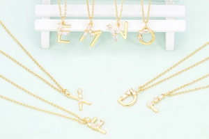 Gold 18K plated alphabet necklace with zircon micro-pave pendants on a green background