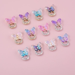 Macro shot of 12 colorful laser butterfly nail charms with rhinestones on pink background