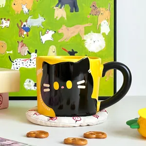 Detail of creative yellow ceramic cat mug with black handle and kitten illustration