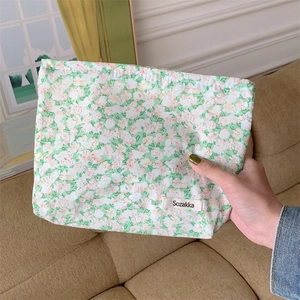 Close-up of a floral cotton makeup bag with green background and pink flower patterns