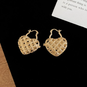 Detailed close-up of gold hollow woven heart earrings on a premium black velvet background
