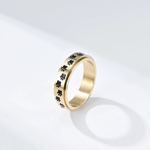 Anillo giratorio de acero de titanio dorado con huellas de patas negras sobre fondo blanco