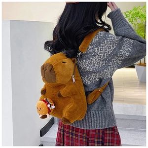 Detail of Capybara plush backpack with a mini burger charm shown on a model's back