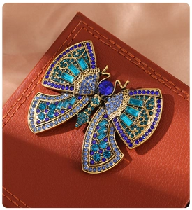 Macro shot of vintage gold butterfly brooch with blue rhinestones on leather background