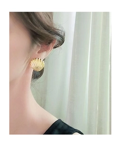 Detailed close-up of golden vintage shell texture earrings worn by a female model