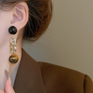 Detailed view of silver needle chain earrings with amber resin links and tiger eye stone