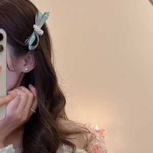 Detail of light blue mesh bow hair clip with pearls worn by model for an elegant look