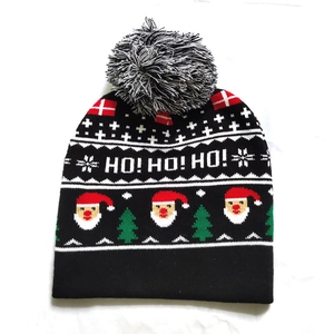 Detail of a black knitted Christmas hat with Santa motifs and white HO! HO! HO! text