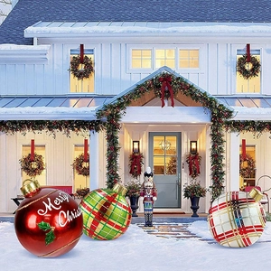 Three large inflatable Christmas balls with festive patterns on a snowy front porch